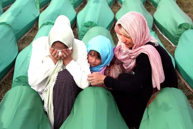 Una famiglia davanti a una delle bare al Centro memoriale di Potočari, durante il funerale delle vittime del massacro di Srebrenica, l'11 luglio 2011 (foto Ansa)