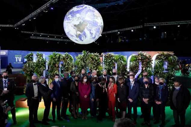 Nancy Pelosi, Speaker of the United States House of Representatives, center in red, and U.S. Rep. Alexandria Ocasio-Cortez, sixth left, and other US politicians pose for a group photo after arriving at the venue of the COP26 U.N. Climate Summit in Glasgow, Scotland, Tuesday, Nov. 9, 2021. The U.N. climate summit in Glasgow has entered it's second week as leaders from around the world, are gathering in Scotland's biggest city, to lay out their vision for addressing the common challenge of global warming. (AP Photo/Alberto Pezzali)