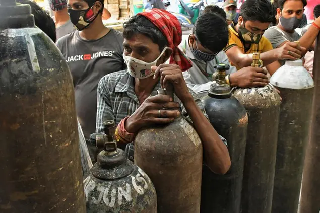 Indians wait to refill oxygen cylinders for COVID-19 patients at a gas supplier facility in New Delhi, India, Saturday, May 8, 2021. Infections have swelled in India since February in a disastrous turn blamed on more contagious variants as well as government decisions to allow massive crowds to gather for religious festivals and political rallies. (AP Photo/Ishant Chauhan)