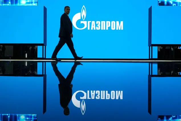 A man walks at an exhibition at the St. Petersburg International Gas Forum in St. Petersburg, Russia, Wednesday, Sept. 14, 2022, with a logo of Russian gas monopoly Gazprom in the background. (AP Photo/Dmitri Lovetsky)