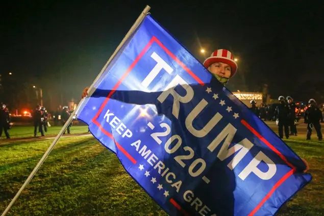 A Trump supporter carries a flag during a protest on Election Day, Tuesday, Nov. 3, 2020, in Beverly Hills, Calif.. (AP Photo/Ringo H.W. Chiu)