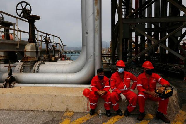 Venezuelan oil workers take a break at El Palito refinery during the arrival of Iranian oil tanker Fortune near Puerto Cabello, Venezuela, Monday, May 25, 2020. Fortune, the first of five tankers loaded with gasoline sent from Iran is expected to temporarily ease Venezuela's fuel crunch while defying Trump administration sanctions targeting the two U.S. foes. (AP Photo/Ernesto Vargas)