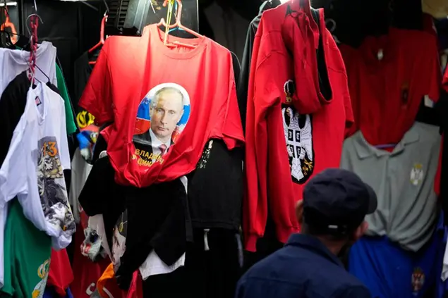 A man looks at a shirt with a picture of Russian President Vladimir Putin displayed on Belgrade's main pedestrian street, Serbia, Saturday, Feb. 26, 2022. Besides Belarus, Serbia is the only other European state that has so far failed to specifically denounce the Russian intervention in Ukraine or join international sanctions against Moscow. (AP Photo/Darko Vojinovic)