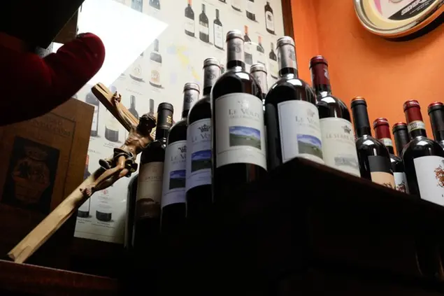 A crucifix leans on wine bottles inside a bar in Rome, Wednesday, Jan. 4, 2023. (AP Photo/Gregorio Borgia)