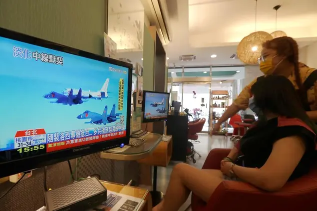 A customer and a staff member watch a news report on the recent tensions between China and Taiwan, at a beauty salon in Taipei, Taiwan, Thursday, Aug. 4, 2022. Taiwan canceled airline flights Thursday as the Chinese navy fired artillery near the island in retaliation for a top American lawmakerâ€™s visit. (AP Photo/Chiang Ying-ying)