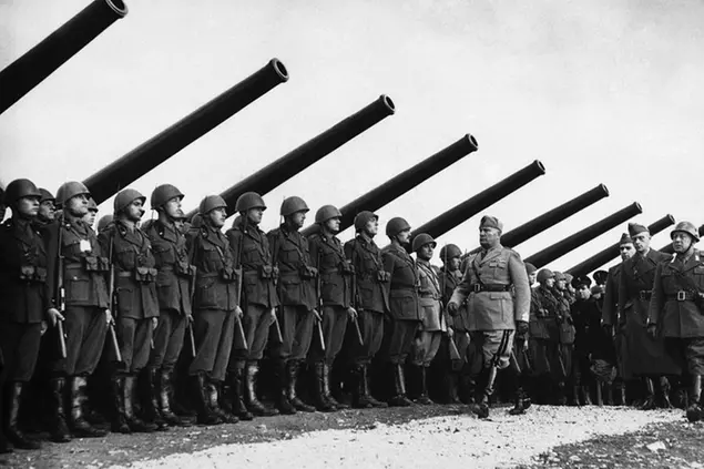 Italian Prime Minister Benito Mussolini reviews Italian troops standing in line beneath massed artillery near the Yugoslav Frontier at Fiume, on Nov. 4, 1940. (AP Photo)