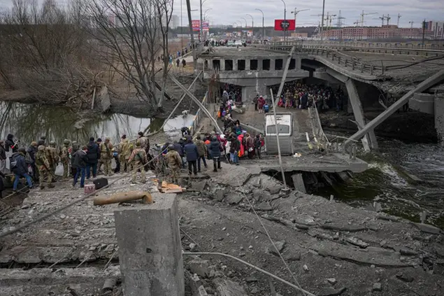 People cross on an improvised path under a bridge that was destroyed by a Russian airstrike, while fleeing the town of Irpin, Ukraine, Saturday, March 5, 2022. What looked like a breakthrough cease-fire to evacuate residents from two cities in Ukraine quickly fell apart Saturday as Ukrainian officials said shelling had halted the work to remove civilians hours after Russia announced the deal. (AP Photo/Vadim Ghirda)