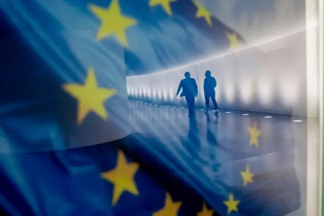 02 July 2020, Berlin: Two people walk through the underground connection between the Reichstag building and the Paul L'be House, where they are reflected in an EU flag which is displayed on an information wall. Photo by: Christoph Soeder/picture-alliance/dpa/AP Images