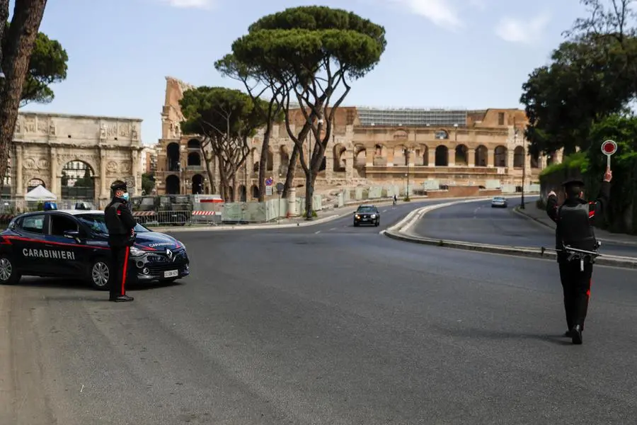 Carabinieri police officers stop a car at a road block near the Colosseum, in downtown Rome, Saturday, April 3, 2021. Italy went into lockdown on Easter weekend in its effort to battle then Covid-19 pandemic. (AP Photo/Gregorio Borgia)