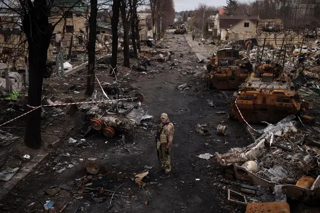 File - A Ukrainian serviceman stands amid destroyed Russian tanks in Bucha, on the outskirts of Kyiv, Ukraine, Wednesday, April 6, 2022. War has been a catastrophe for Ukraine and a crisis for the globe. One year on, thousands of civilians are dead, and countless buildings have been destroyed. Hundreds of thousands of troops have been killed or wounded on each side. Beyond Ukraine’s borders, the invasion shattered European security, redrew nations’ relations with one another and frayed a tightly woven global economy. (AP Photo/Felipe Dana, File)