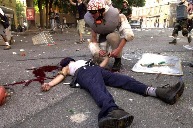 EDS NOTE: GRAPHIC CONTENT -- An anti-globalization activist leans over a dying demonstrator after clashes with the police in downtown Genoa, Italy, Friday, July 20, 2001. Tens of thousands demonstrators took to the streets to protest against the G8 summit. The demonstrator died soon after. (AP Photo/Alessandro Digaetano)