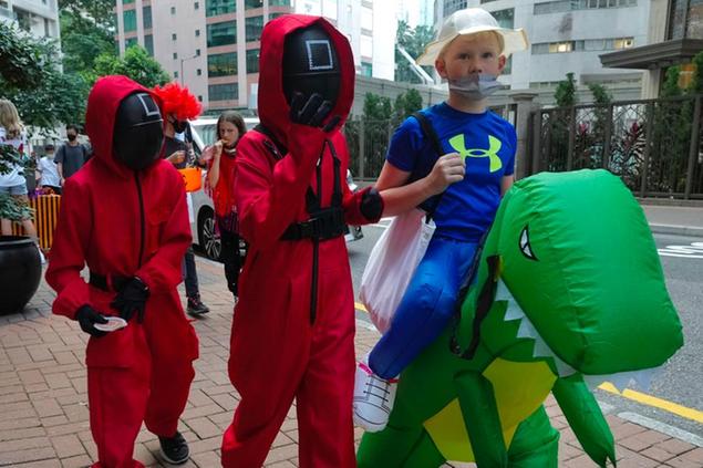 Children dress in costumes inspired by the Netflix original Korean series \\\"Squid Game\\\" walk along a street to celebrate Halloween in Hong Kong, Sunday, Oct. 31, 2021. (AP Photo/Vincent Yu)