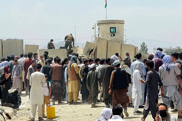Afghan security guards stand on a wall as hundreds of people gather outside the international airport in Kabul, Afghanistan, Tuesday, Aug. 17, 2021. The Taliban declared an “amnesty” across Afghanistan and urged women to join their government Tuesday, seeking to convince a wary population that they have changed a day after deadly chaos gripped the main airport as desperate crowds tried to flee the country. (AP Photo)