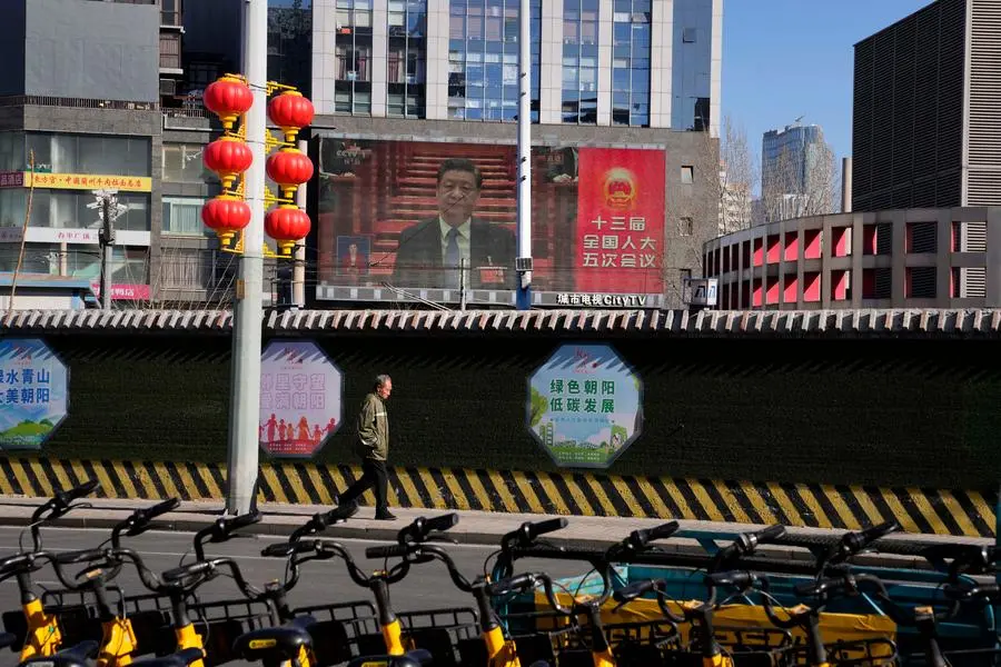 A man walks past a large video screen showing Chinese President Xi Jinping at the opening session of the annual meeting of China\\\\'s National People\\\\'s Congress (NPC) in Beijing, Saturday, March 5, 2022. (AP Photo/Ng Han Guan)