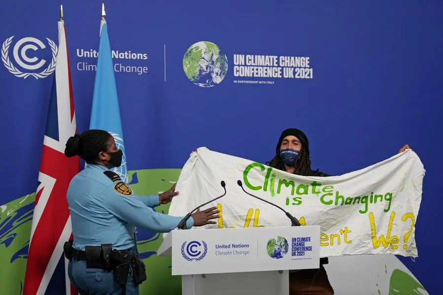 A member of security moves to apprehend a demonstrator at the COP26 U.N. Climate Summit in Glasgow, Scotland, Saturday, Nov. 13, 2021. Almost 200 nations have accepted a contentious climate compromise aimed at keeping a key global warming target alive, but it contained a last-minute change that watered down crucial language about coal. (AP Photo/Alastair Grant)