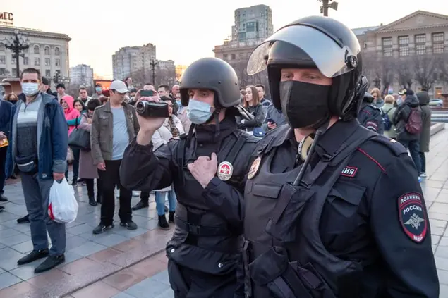 A Russian police officer films people ahead of the possible opposition rally in support of jailed opposition leader Alexei Navalny in Khabarovsk, 6,100 kilometers (3,800 miles) east of Moscow, Russia, Wednesday, April 21, 2021. Navalny's team has called for nationwide protests on Wednesday following reports that the politician's health was deteriorating in prison, where he has been on hunger strike since March 31. Russian authorities have stressed that the demonstrations were not authorized and warned against participating in them. (AP Photo/Igor Volkov)