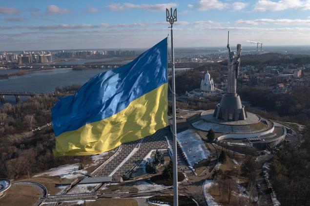 A view of Ukraine's national flag waves above the capital with the Motherland Monument on the right, in Kyiv Sunday, Feb. 13, 2022. Some airlines have halted or diverted flights to Ukraine amid heightened fears that an invasion by Russia is imminent despite intensive weekend talks between the Kremlin and the West. (AP Photo/Efrem Lukatsky)