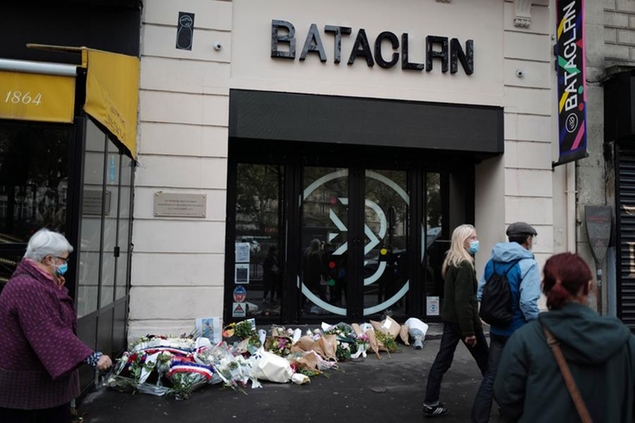 FILE - In this file photo dated Friday, Nov. 13, 2020, passers by walk outside the Bataclan concert hall with wreaths of flowers marking the 5th anniversary of the Nov. 13, 2015, Islamic State extremists attacks in Paris. The European Commission said Wednesday Dec. 9, 2020, it wants member states to reinforce border controls to better protect the 27-nation bloc from extremist attacks like the Paris attacks five years ago and other extremist actions. (AP Photo/Francois Mori, FILE)