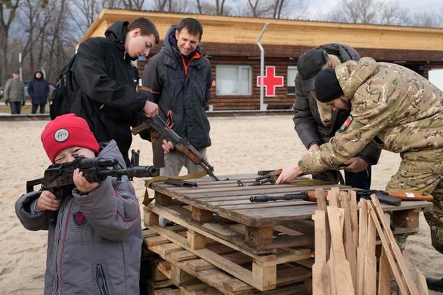 A boy plays with a weapon while an instructor shows a Kalashnikov assault rifle during a training of members of a Ukrainian far-right group train, in Kyiv, Ukraine, Sunday, Feb. 20, 2022. Russia extended military drills near Ukraine\\\\'s northern borders Sunday amid increased fears that two days of sustained shelling along the contact line between soldiers and Russa-backed separatists in eastern Ukraine could spark an invasion. (AP Photo/Efrem Lukatsky)