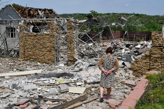 FILE - An elderly woman walks next to a building damaged by an overnight missile strike in Slovyansk, Ukraine, Wednesday, June 1, 2022. (AP Photo/Andriy Andriyenko, File)