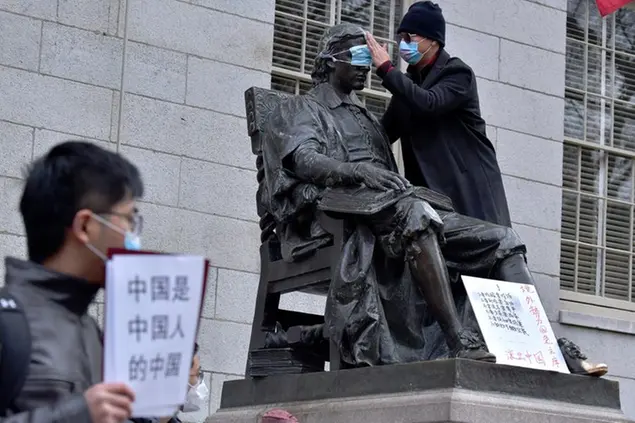 A man places a mask over the eyes of the John Harvard Statue in Harvard Yard as dozens of students and faculty demonstrate against strict anti-virus measures in China, Tuesday, Nov. 29, 2022, at Harvard University in Cambridge, Mass. Protests in China, which were the largest and most wide spread in the nation in decades, included calls for Communist Party leader Xi Jinping to step down. (AP Photo/Josh Reynolds) Associated Press/LaPresse Only Italy and Spain