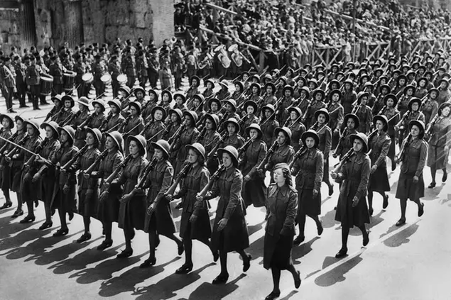 70,000 fascist women and girls marched past Italian dictator Benito Mussolini on the Via dell’impero, in military massed formation led by bands and standard bearers. A company of khaki-dressed girls in sun helmets and carrying rifles with fixed bayonets received a particular ovation from the crowd. The parade was held to celebrate the twentieth anniversary of Fascism, and when it was over, Il Duce drove back through cheering crowds to the Palazzo Venezia, where he had to appear several times on his balcony to satisfy the demands of the 70,000 women and girls who gathered in the huge square under his window. The khaki-dressed girls in sun helmets and carrying rifles with fixed bayonets, waking part in the parade in Rome, Italy, on May 28, 1939. (AP Photo)