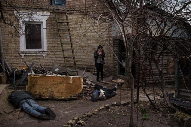 Ira Gavriluk holds her cat as she walks among the bodies of her husband, brother, and another man, who were killed outside her home in Bucha, on the outskirts of Kyiv, Ukraine, Monday, April 4, 2022. (AP Photo/Felipe Dana)