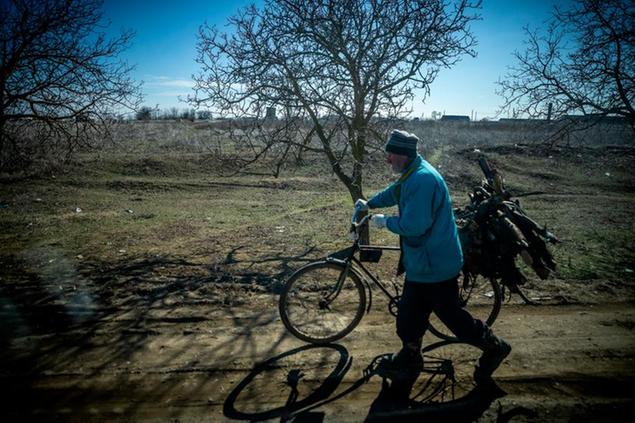 12 March 2022, Moldova, Palanca: A man transports firewood on his bicycle in a rural setting, near the border between Moldova and Ukraine. Foreign Minister Annalena Baerbock visited the border crossing in Palanca on the same day to learn about the situation of refugees. The focus of her talks in Moldova is the war in Ukraine and the situation of refugees in the country. Photo by: Michael Kappeler/picture-alliance/dpa/AP Images