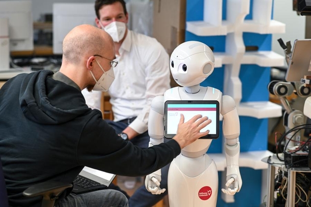 PRODUCTION - 26 May 2021, Baden-Wuerttemberg, Weingarten: Benjamin St'hle (l), deputy head of the Institute for Artificial Intelligence at the Ravensburg-Weingarten University of Applied Sciences, and Julian Kr'ger, head of the Magdalena nursing home in Ehningen, test the Pepper nursing robot at the university in Weingarten. (to dpa \\\"Helpers without risk of infection: Is the hour of the robots now?\\\") Photo by: Felix K'stle/picture-alliance/dpa/AP Images