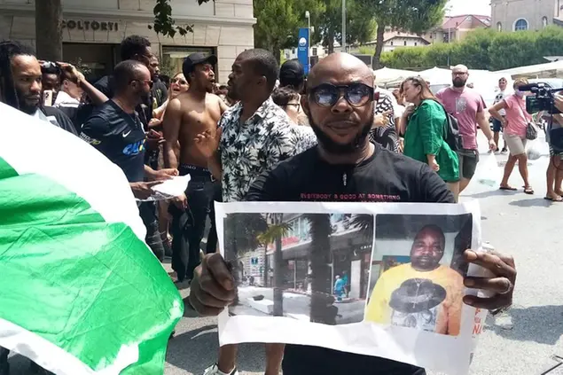 A man shows a picture of the victim Nigerian street vendor Alika Ogorchukwu, in Civitanova Marche, Italy, Saturday, July 30, 2022. (AP Photo/Chiara Gabrielli)