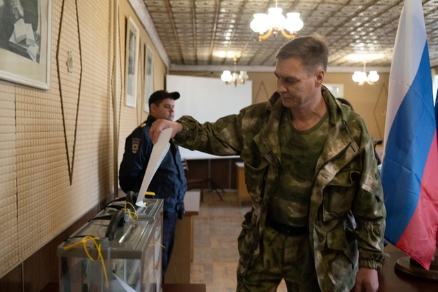 A Luhansk People's Republic serviceman votes in a polling station in Luhansk, Luhansk People's Republic, controlled by Russia-backed separatists, eastern Ukraine, Friday, Sept. 23, 2022. Voting began Friday in four Moscow-held regions of Ukraine on referendums to become part of Russia. (AP Photo)
