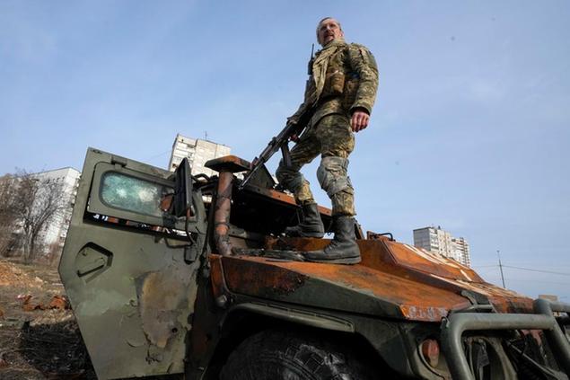 A Ukrainian soldier stands a top a destroyed Russian APC after recent battle in Kharkiv, Ukraine, Saturday, March 26, 2022. With Russia continuing to strike and encircle urban populations, from Chernihiv and Kharkiv in the north to Mariupol in the south, Ukrainian authorities said Saturday that they cannot trust statements from the Russian military Friday suggesting that the Kremlin planned to concentrate its remaining strength on wresting the entirety of Ukraine's eastern Donbas region from Ukrainian control. (AP Photo/Efrem Lukatsky)