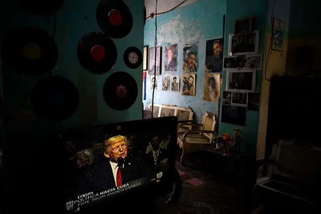 FILE - In this June 16, 2017 file photo, a television set shows U.S. President Donald Trump announcing his new Cuba policy, in a living room decorated with images of Cuban leaders at a home in Havana, Cuba. Both U.S. sanctions meant to punish the government and a COVID-19 pandemic have squashed tourism almost everywhere, making some Cubans hope that new U.S. President Joe Biden will reverse at least some of the restrictions implemented by his predecessor. (AP Photo/Ramon Espinosa, File)