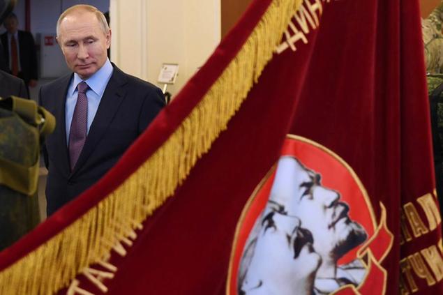 Russian President Vladimir Putin looks at a Soviet era banner depicting Soviet Union founder Vladimir Lenin and Soviet dictator Joseph Stalin during his visit to the company \\\"Polyot\\\", manufacturing parachute systems, in Ivanovo, 254 kilometers (158 miles) northeast of Moscow, Russia, Friday, March 6, 2020. Russian President Vladimir Putin said Friday he doesn't want to scrap presidential term limits or resort to other suggested ways of extending his rule, but otherwise he kept mum about his plans. (Alexei Nikolsky, Sputnik, Kremlin Pool Photo via AP)