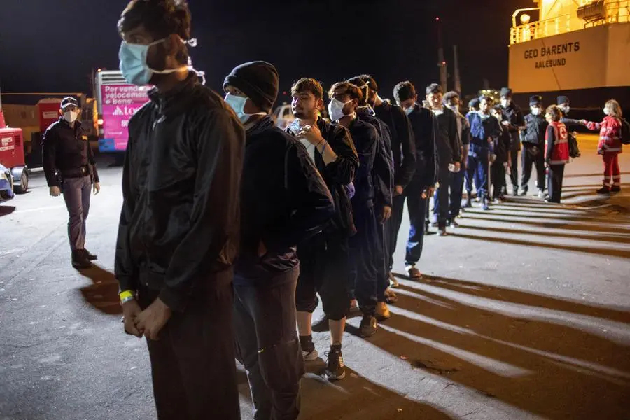 CORRECTS NAME OF PHOTOGRAPHER - Migrants line up after disembarking from the Norway-flagged Geo Barents rescue ship after having been allowed by Italian authorities, in Catania's port, Sicily, southern Italy, Tuesday, Nov. 8, 2022. While the Geo Barents was allowed to disembark all its migrants, the German-flagged Humanity1 is still at harbor in Catania with 35 aboard still waiting for permission, and another rescue ship, the Ocean Viking is appealing France for a safe port. (AP Photo/Massimo di Nonno)