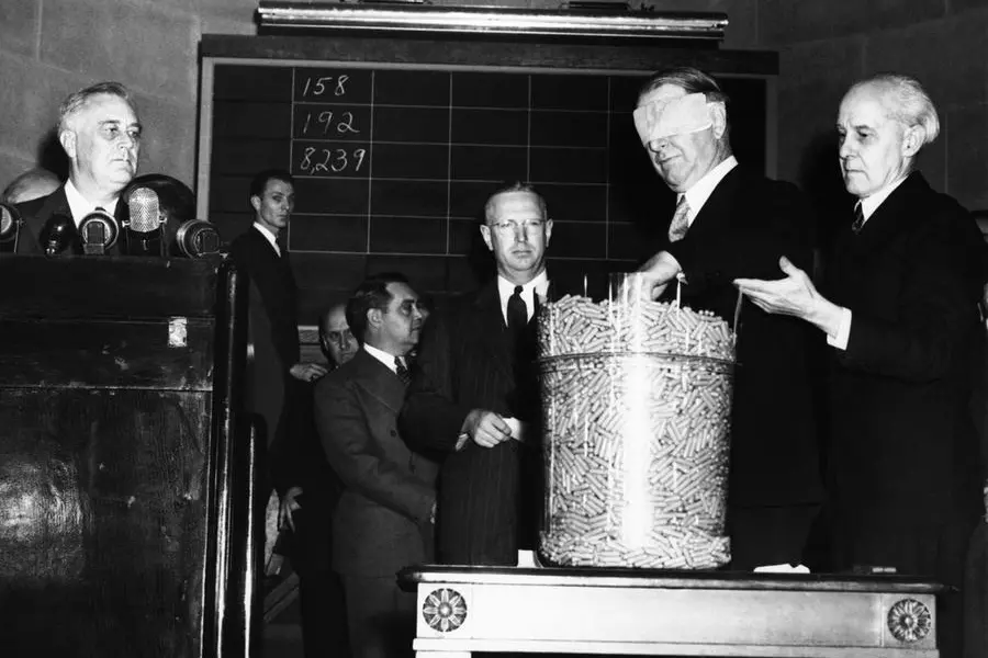 Secretary of navy Frank Knox (blindfolded) draws the fourth number?6620?in the national lottery for compulsory military training on Oct. 29, 1940. President Roosevelt, left, read the first few numbers picked. From Left to Right are: President Roosevelt; Maj. Edward S. Shattuck, who read later numbers; Knox; and Lieut. Col. R. Morris, retired, who blindfolded dignitaries as he did in the world war draft. (AP Photo)