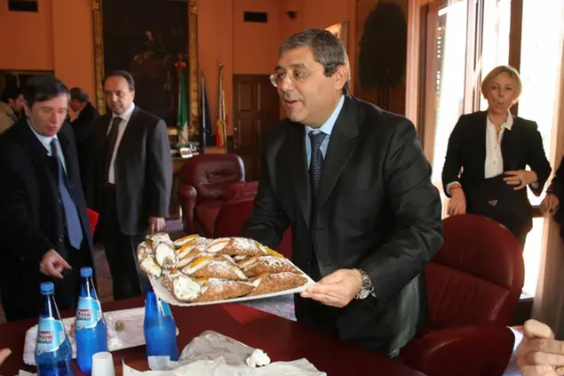 Salvatore Cuffaro nella celebre foto in cui offre cannoli il giorno dopo essere stato condannato a 5 anni per favoreggiamento semplice a Palermo, in una foto d'archivio del 19 gennaio 2008 foto ansa