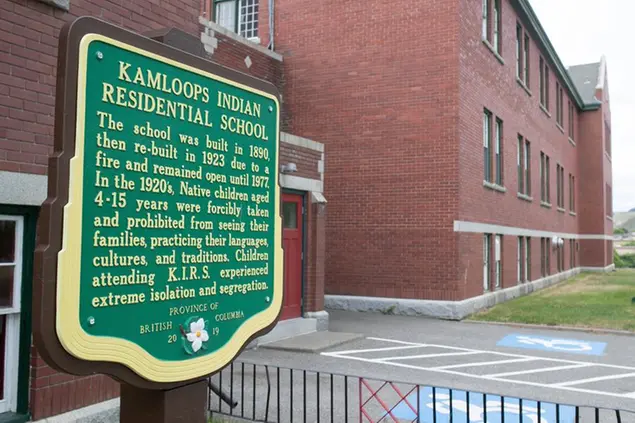 A plaque is seen outside of the former Kamloops Indian Residential School on Tk'emlups te Secwépemc First Nation in Kamloops, British Columbia, Canada on Thursday, May 27, 2021. The remains of 215 children have been found buried on the site of the former residential school in Kamloops. (Andrew Snucins/The Canadian Press via AP)