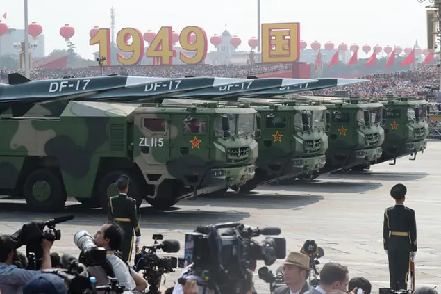 Military vehicles, carrying DF-17, roll down as members of a Chinese military honor guard march during the parade to commemorate the 70th anniversary of the founding of Communist China in Beijing, Tuesday, Oct. 1, 2019. China's military has shown off a new hypersonic ballistic nuclear missile believed capable of breaching all existing anti-missile shields deployed by the U.S. and its allies. The vehicle-mounted DF-17 was among weapons displayed Tuesday in a massive military parade marking the 70th anniversary of the founding of the Chinese state.(AP Photo/Ng Han Guan)