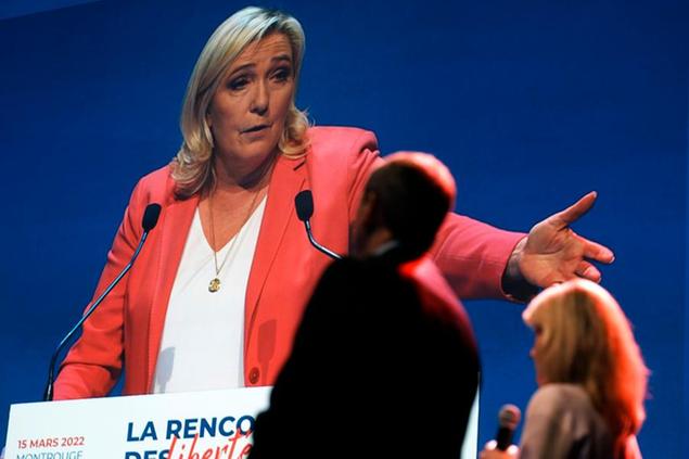 French far-right presidential candidate Marine Le Pen is seen on a screen as she speaks during a meeting with French mayors, in Montrouge, south of Paris, Tuesday, March 15, 2022. The two-round presidential election will take place on April 10th and 24th 2022. (AP Photo/Thibault Camus)
