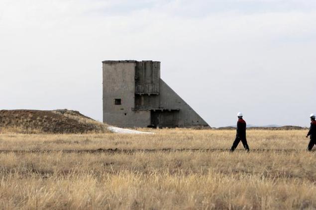 Workers pass a structure at the former Semipalatinsk nuclear bomb testing center, during a visit by U.N. Secretary General Ban Ki-moon, 90 miles (144 kilometers) from Kurchatov, Kazakhstan, Tuesday, April 6, 2010. Ban arrived in Kazakhstan Tuesday, where he praised U.S. President Barack Obama's new nuclear weapons policy. (AP Photo/Alexander Zemlianichenko)
