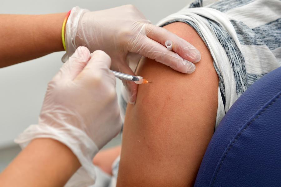 Bambini in fila davanti a un centro vaccinale, con medici e infermieri che somministrano le iniezioni