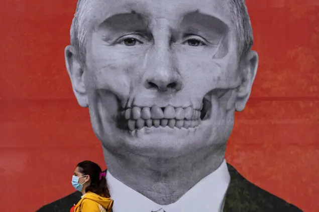 A woman walks by an artistic depiction of Russian President Vladimir Putin by Kriss Salmanis of Latvia, outside the Russian embassy in Bucharest, Romania, Friday, April 29, 2022. (AP Photo/Vadim Ghirda)