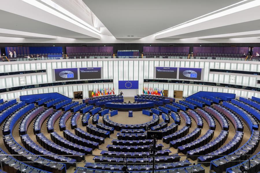 Aula del Parlamento europeo vuota durante la pausa estiva, banchi deserti sotto l'illuminazione artificiale