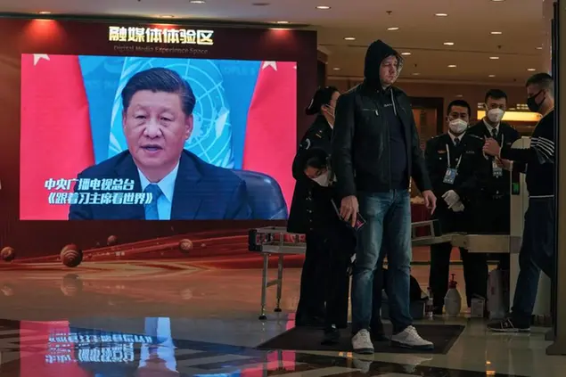 Security personnel check on foreign journalists who cover the closing ceremony of the 20th National Congress of China's ruling Communist Party near a TV screen showing image of President Xi Jinping at a media hotel in Beijing, Friday, Oct. 21, 2022. The Chinese Communist Party is holding its every-five-year national congress which will unveil new leadership for the coming five years. (AP Photo/Andy Wong)