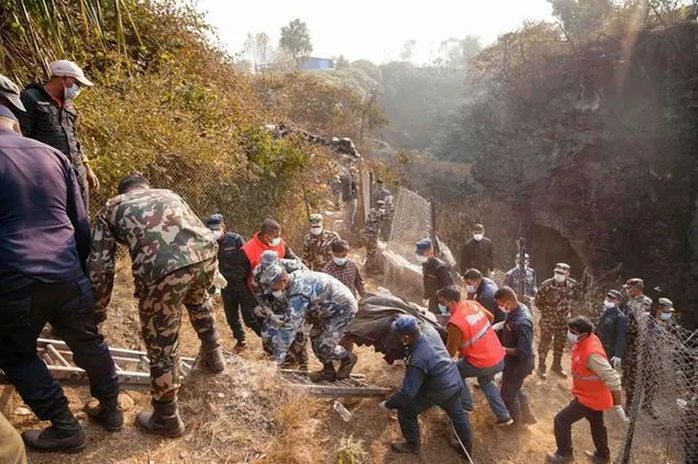 Rescue workers recover the body of a victim of a passenger plane that crashed in Pokhara, Nepal, Sunday, Jan. 15, 2023. A plane making a 27-minute flight to a Nepal tourist town crashed into a gorge Sunday while attempting to land at a newly opened airport, killing at least 68 of the 72 people aboard. At least one witness reported hearing cries for help from within the fiery wreck, the country’s deadliest airplane accident in three decades. (AP Photo/Yunish Gurung)