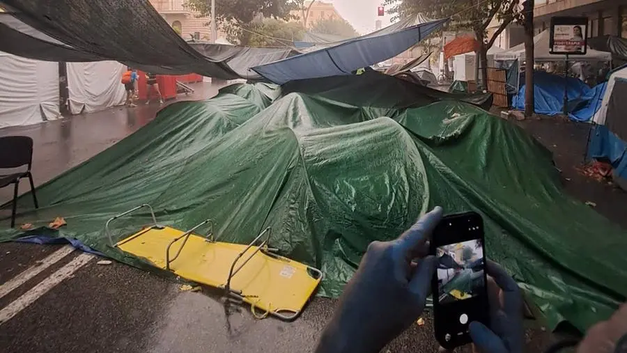 Sfollati di Spin Time sotto la pioggia, tende e persone in strada, Roma