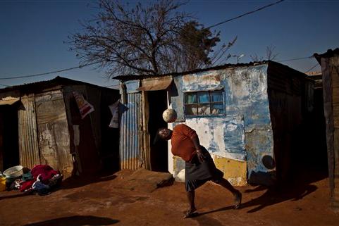 A South African woman, bounces the ball on her head while playing with a football with other women, not seen, next to their homes in a Soweto township on the outskirts of Johannesburg, South Africa, Thursday, July 4, 2013. (AP Photo/Muhammed Muheisen)