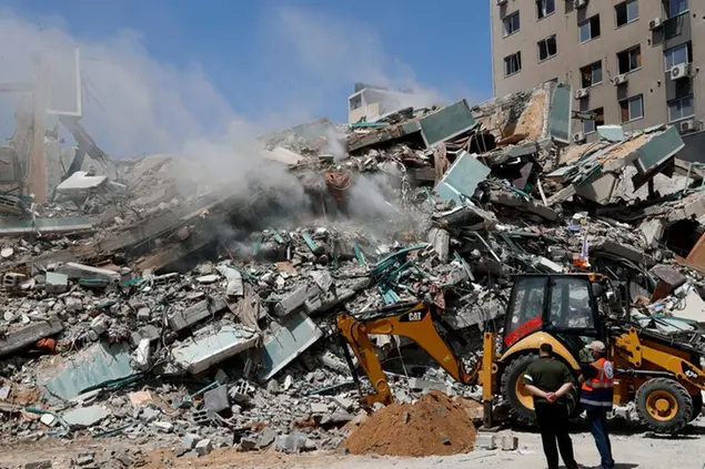 Workers clear the rubble of a building that was destroyed by an Israeli airstrike on Saturday, that housed The Associated Press, broadcaster Al-Jazeera and other media outlets, in Gaza City, Sunday, May 16, 2021. (AP Photo/Adel Hana)