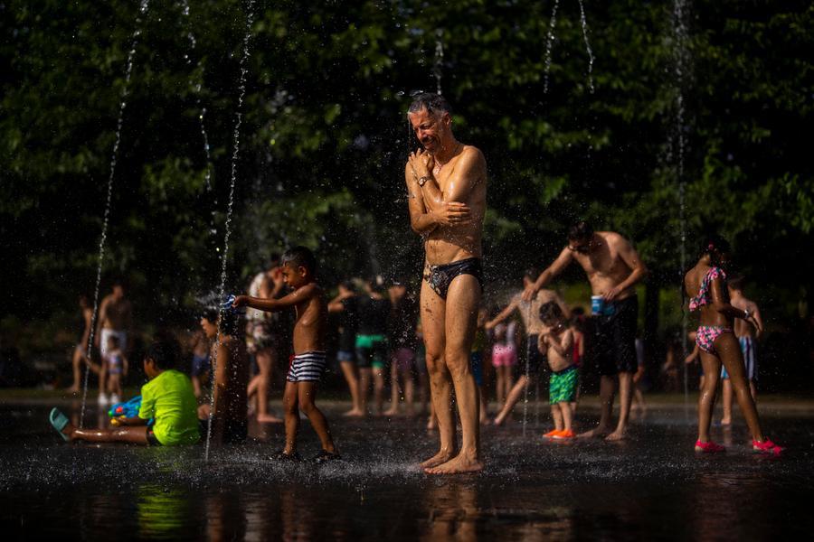 Children and adults cool off in a fountain in a park by the river in Madrid, Spain, Friday, June 17, 2022. The current heat wave in Europe started almost a week ago in Spain, where temperatures reached 43 C (109.4F). Spanish authorities hope the weather will begin to cool again Sunday. (AP Photo/Manu Fernandez)